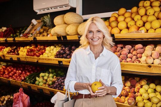 Blonde woman exploring fresh organic produce at a vibrant farmers market grocery store