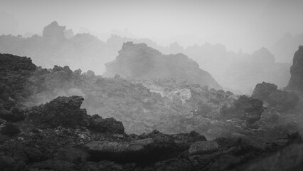 Dramatic landscape of rugged volcanic rocks shrouded in mist, creating an ethereal atmosphere,...