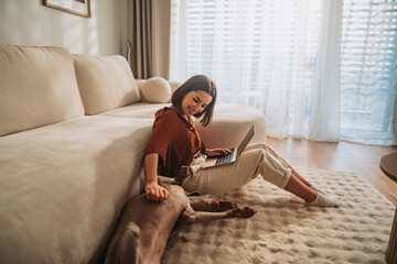 A Young Woman Focused on Working from Home Alongside Her Dog in a Cozy Living Room Space