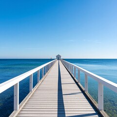 Obraz premium Tranquil white wooden pier extending into a vast blue sea under a clear sky