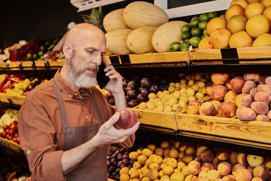 Salesman discusses fresh produce while examining ripe peaches in a grocery store