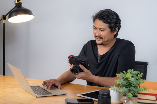 A young male photographer working from home, editing photos on a computer with creative software in a cozy workspace
