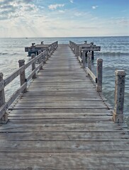 Fototapeta premium Scenic seascape with wooden dock leading to the horizon under soft sunlight
