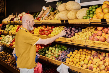 Mature man selecting organic fruits at a vibrant farmers market grocery store