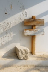 Naklejka premium Weathered wooden signpost against a peeling white wall next to a stone block on a concrete surface