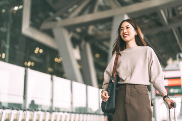 Standing asian business woman with travel luggage waiting at bus terminal for transport on day © dodotone