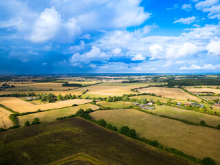 Obraz premium Early evening UAV view of agricultural land in the East of England, with a farm house near the centre of the image. Storm clouds can be seen gathering.