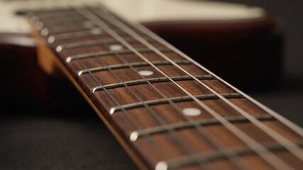 Closeup of a guitar neck with strings and fret markers showcasing its wooden detail and metal frets - Powered by Adobe