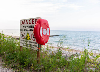 Warning sign with lifebuoy on the beach