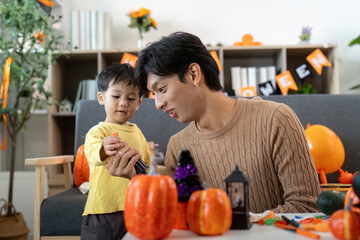 Halloween Fun. Father and son crafting pumpkin decorations at home.