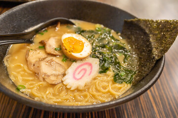 Japanese ramen presented in a rich broth, topped with soft-boiled egg, seaweed, and pork.