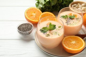 Superfood. Tasty smoothie with chia seeds, mint, pistachio and oranges on white wooden table, closeup