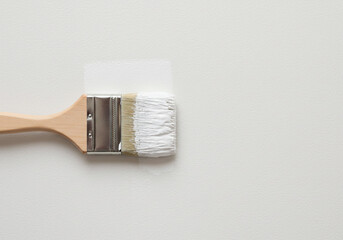 Close up of a paint brush with white paint on a white surface in a studio setting with good lighting