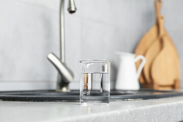 Beaker with clean water near sink on counter in kitchen, closeup
