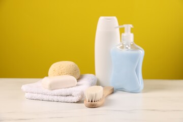 Baby accessories and bathing products on white marble table against yellow background