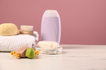 Baby accessories and bathing products on white marble table against pink background, closeup. Space for text