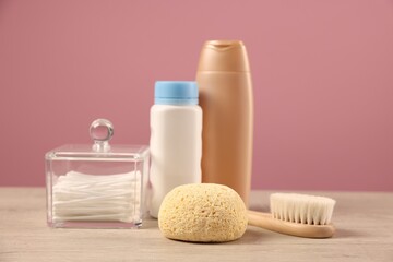 Baby accessories and bathing products on wooden table against pink background