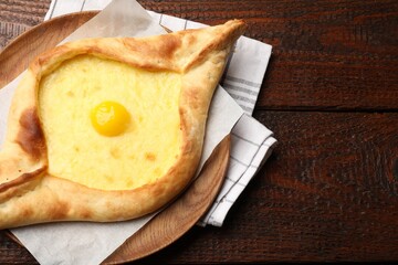 Tasty khachapuri with cheese and egg on wooden table, top view. Space for text