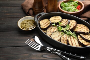 Grilled slices of eggplant with microgreens served on wooden table, closeup