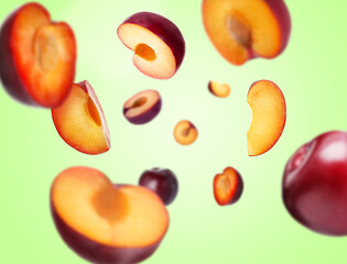 Fresh ripe plums swirling in air against green background