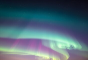 Obraz premium Aurora borealis display with green, purple, and white lights dancing across the night sky.