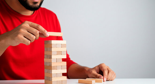 Man carefully playing the block game, building a tower strategically