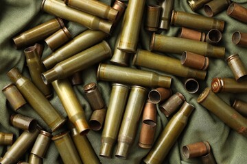 Many used rifle cartridges on military camo green fabric background