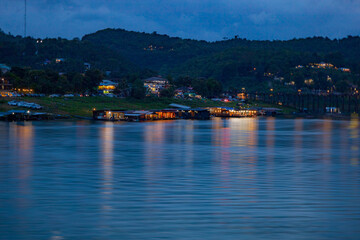 Naklejka premium The Mon village in Kanchanaburi with morning mist on the green mountains and clear river.