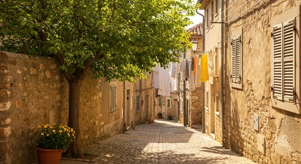 Obraz premium Charming European alley with stone walls, shutters, hanging laundry, and cobblestone street in the sunlight.