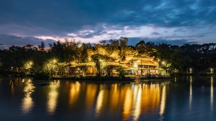 Hefei lakeside restaurant with illuminated buildings and golden water reflections at twilight, China