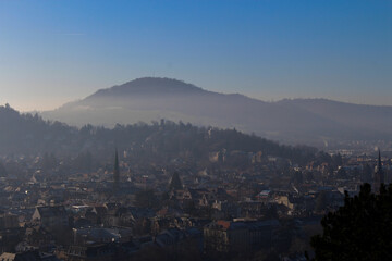 Panoramic view of the foggy city of Freiburg with snow-capped mountain peaks in the background on a winter day 