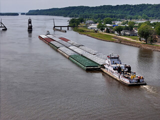 Large set of cargo barges about to be guided through the narrow opening of the railroad swing bridge at Sabula Iowa