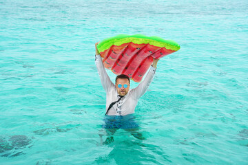 Fototapeta na wymiar Business man with with colorful swimming mattress in tropical beach vacation. Announcement, save your vacation, off on vacation concept.