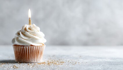 Single cupcake with lit candle, white frosting, gold sprinkles