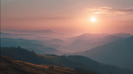 Obraz premium Serene sunset casts warm light over mountain ridge, creating tranquil atmosphere with soft hues and misty layers