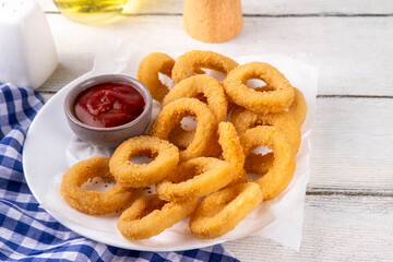 Golden onion rings with ketchup sauce, airfryer cooked tasty onion ring snacks on white wooden table copy space