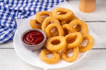 Golden onion rings with ketchup sauce, airfryer cooked tasty onion ring snacks on white wooden table copy space