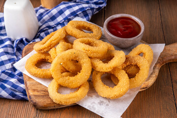 Golden onion rings with ketchup sauce, airfryer cooked tasty onion ring snacks on white wooden table copy space