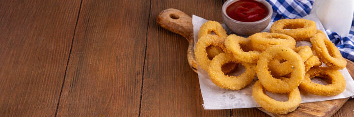 Golden onion rings with ketchup sauce, airfryer cooked tasty onion ring snacks on white wooden table copy space