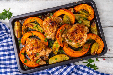 Roasted baked chicken thigh with pumpkin and potato wedges, garlic and aromatic herbs. Tasty autumn...