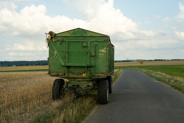 Obraz premium A farmer's large green dump trailer stands in a field. The picture shows the start of the harvest season.