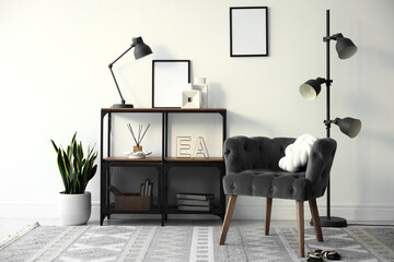 Stylish grey armchair, shelving unit and houseplants indoors. Interior design