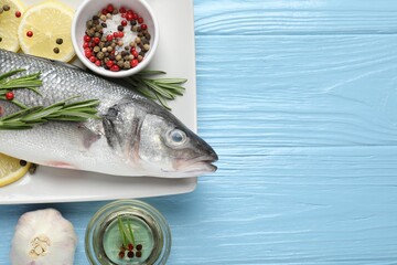 Fresh raw seabass fish with spices on blue wooden table, flat lay and space for text. Seafood delicacies