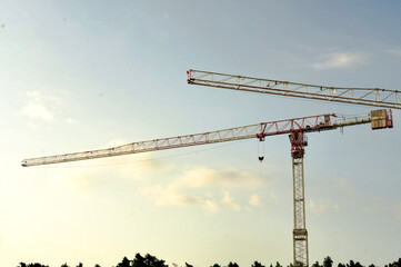 Tower cranes on a construction site against a blue sky.