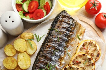 Tasty roasted mackerel served with potatoes and salad on table, flat lay. Homemade seafood dish