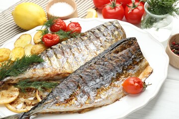 Tasty roasted mackerels with spices, tomatoes and potatoes on white wooden table, closeup. Homemade seafood dish