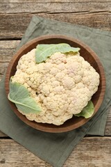 Fresh cauliflower with green leaves on wooden table, top view