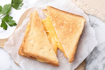 Tasty sandwiches with melted cheese and parsley on white marble table, flat lay
