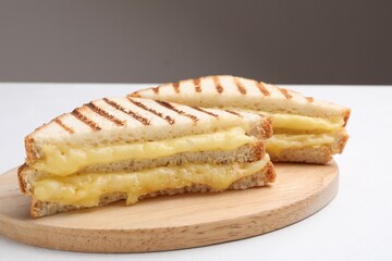 Tasty sandwiches with melted cheese on white table, closeup