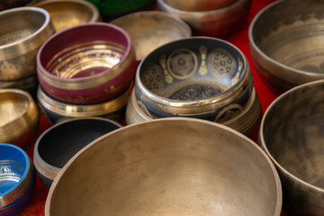 Close up of Tibetan singing bowls in various colors and designs, traditional handcrafted metal bowls used for meditation, sound therapy, and spiritual rituals.